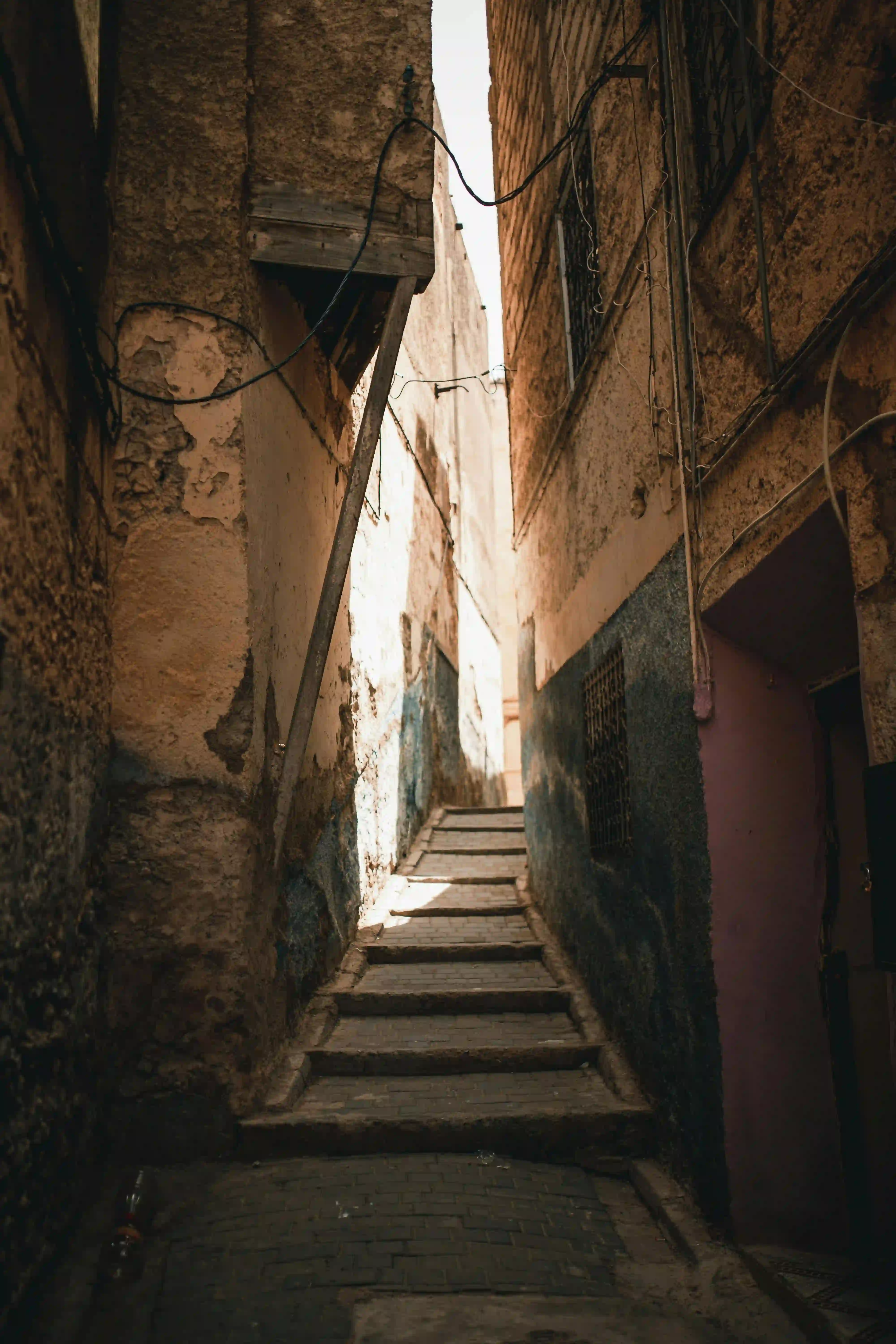 Narrow sunlit alleyway climbing worn stone steps through the Fes medina — slow travel with Local Morocco Tours