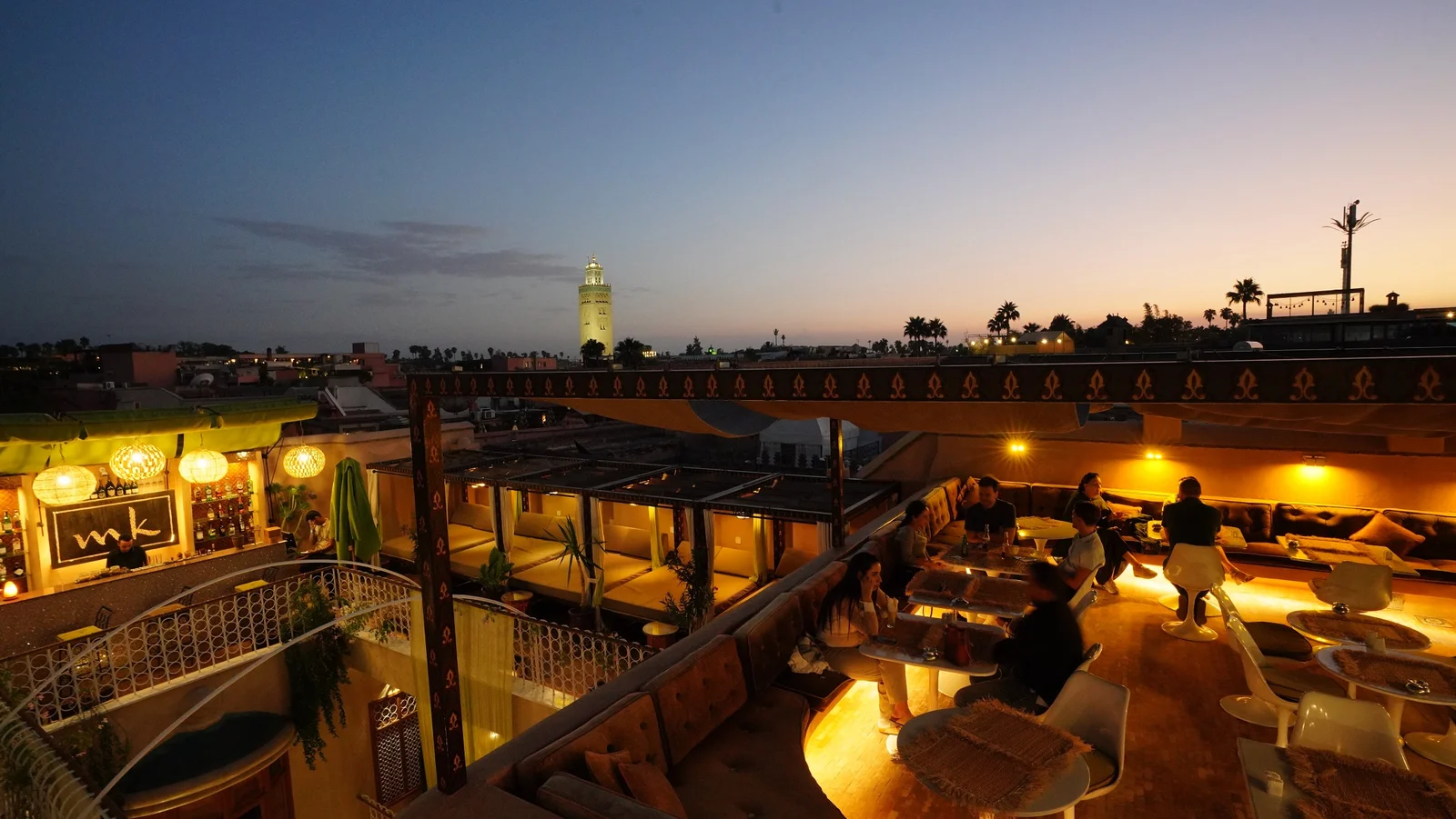 Candlelit Marrakech rooftop lounge at dusk overlooking the Koutoubia minaret — private Morocco tours